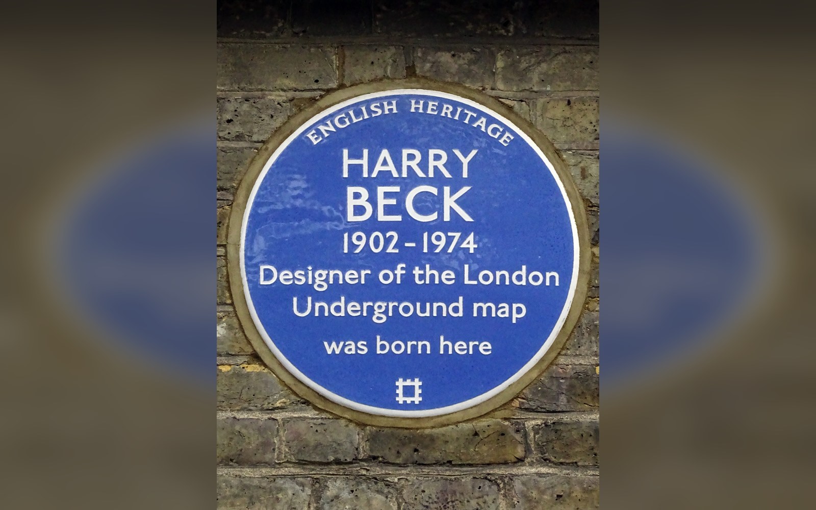 The 1933 London Underground diagram at full poster size on a station hoarding, a commuter's shoulder visible at the right edge giving scale
