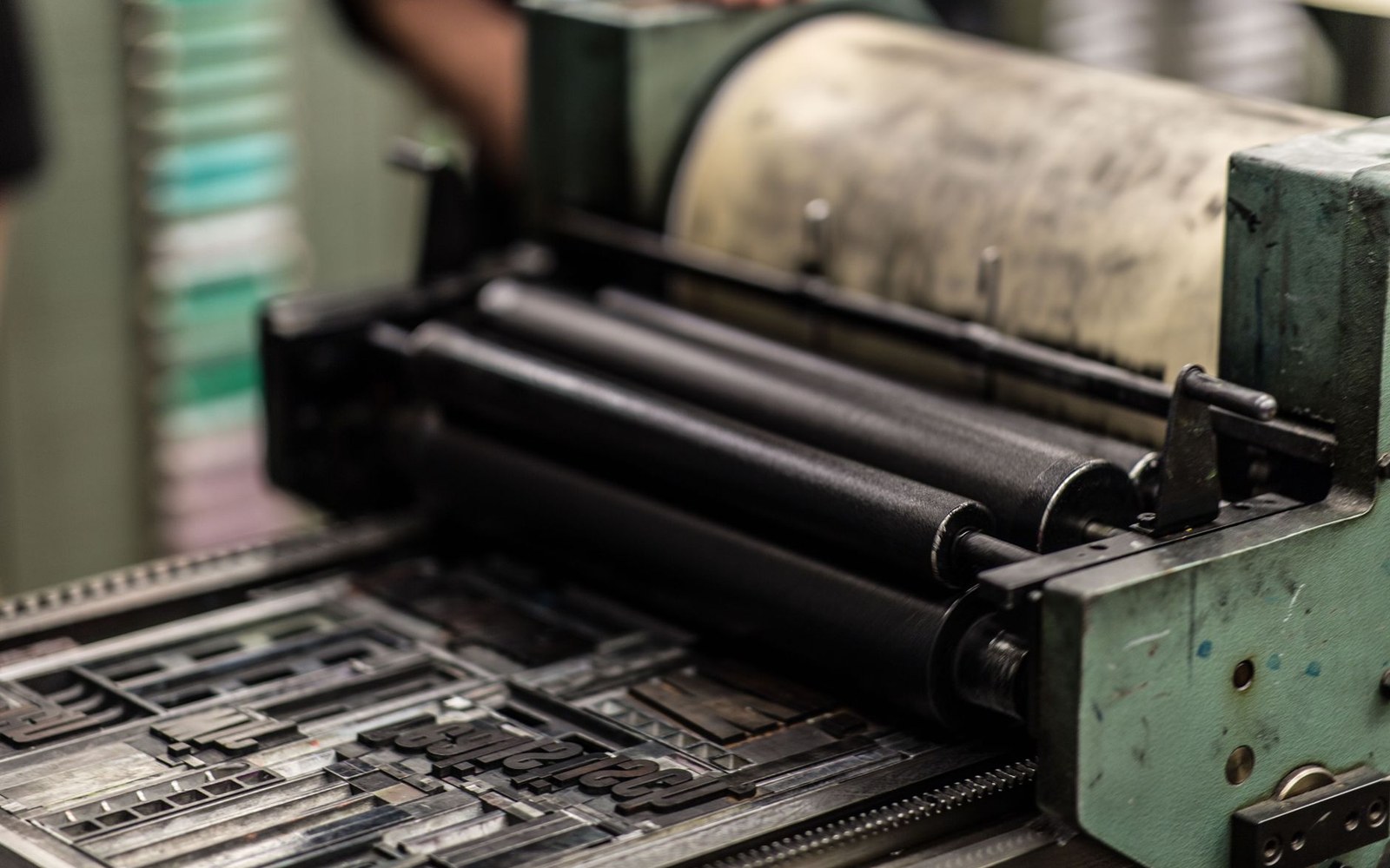 Ink rollers on a letterpress printing machine above a bed of metal type