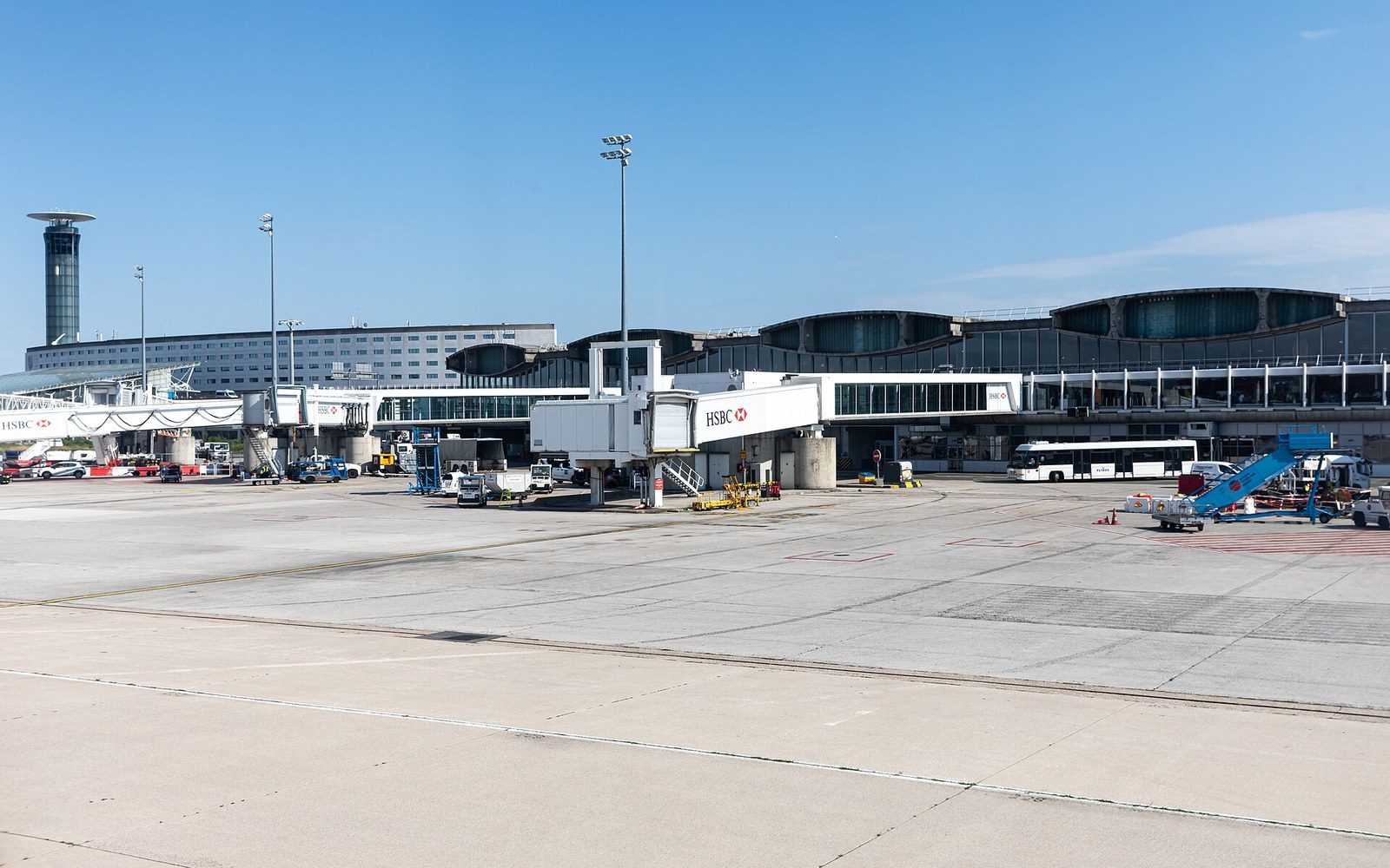 Airport terminal with jet bridges, control tower and ground vehicles parked on the tarmac