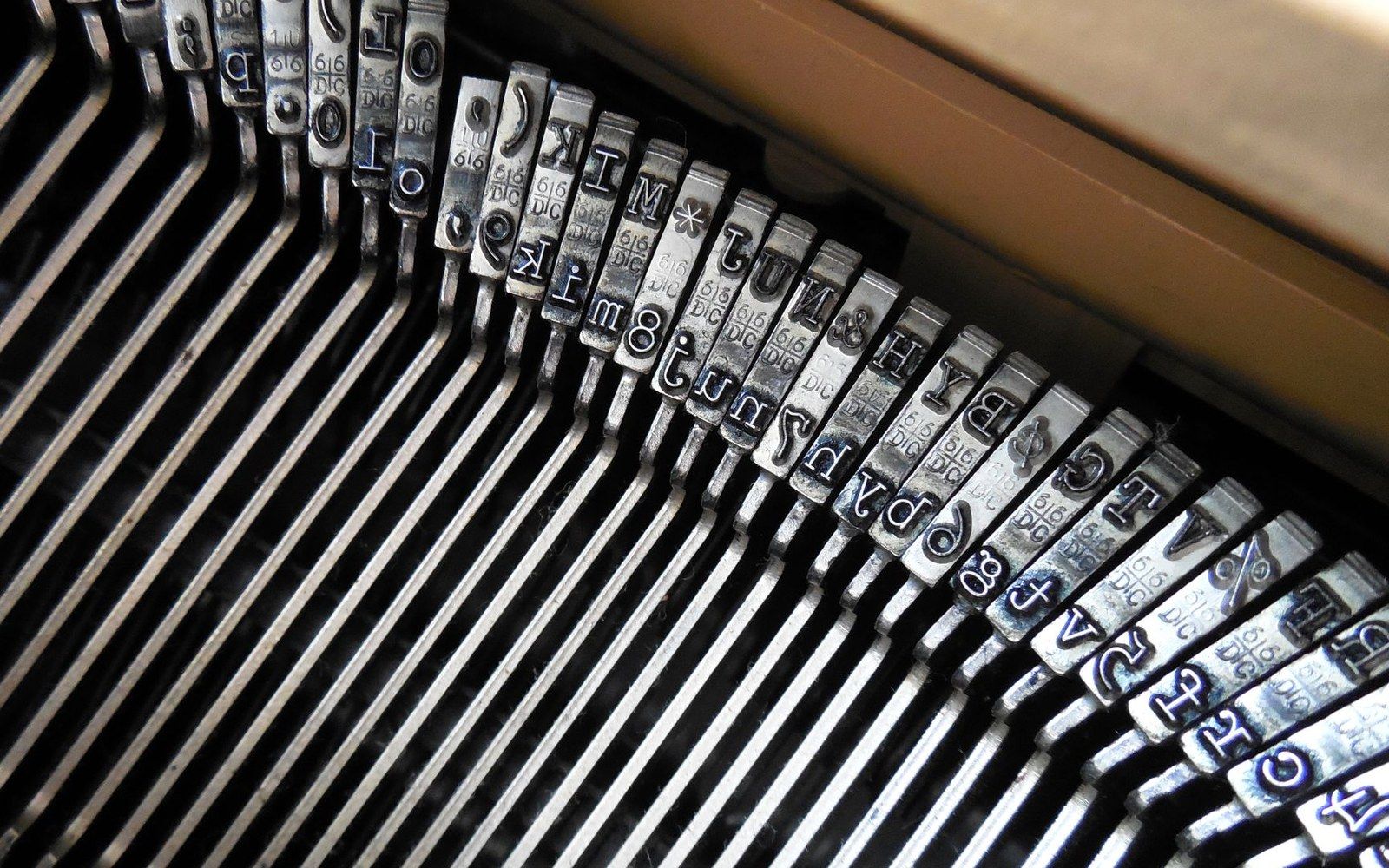 Close-up of a typewriter's metal typebars fanned out with letter and symbol stamps