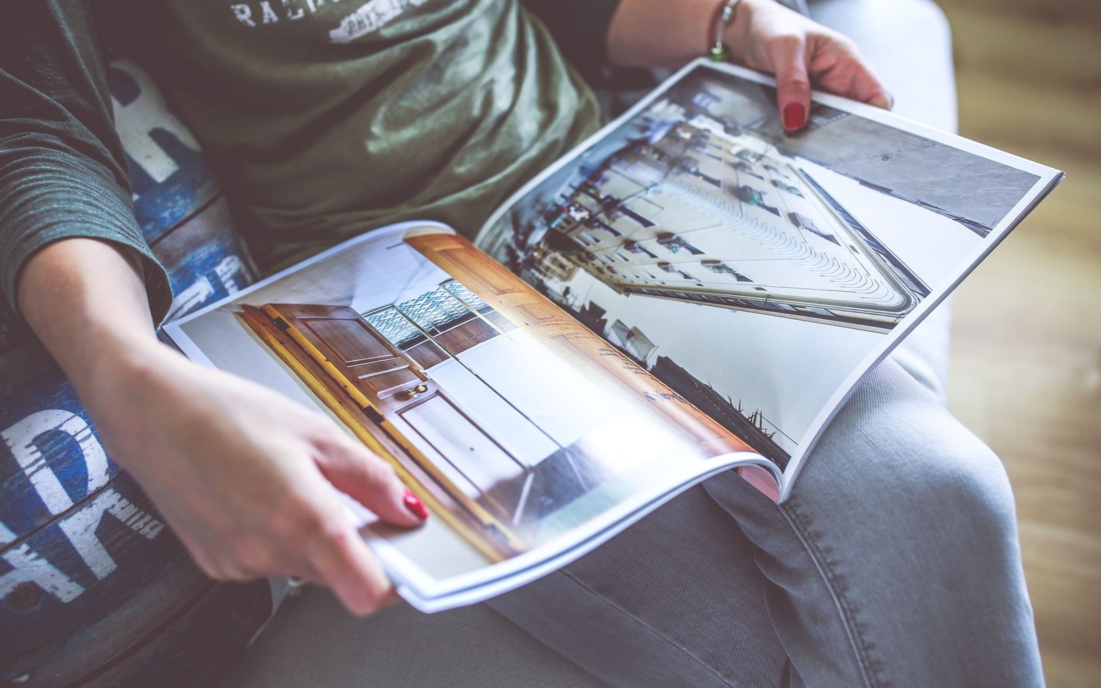 Person with red nail polish holding open a magazine showing photography spreads