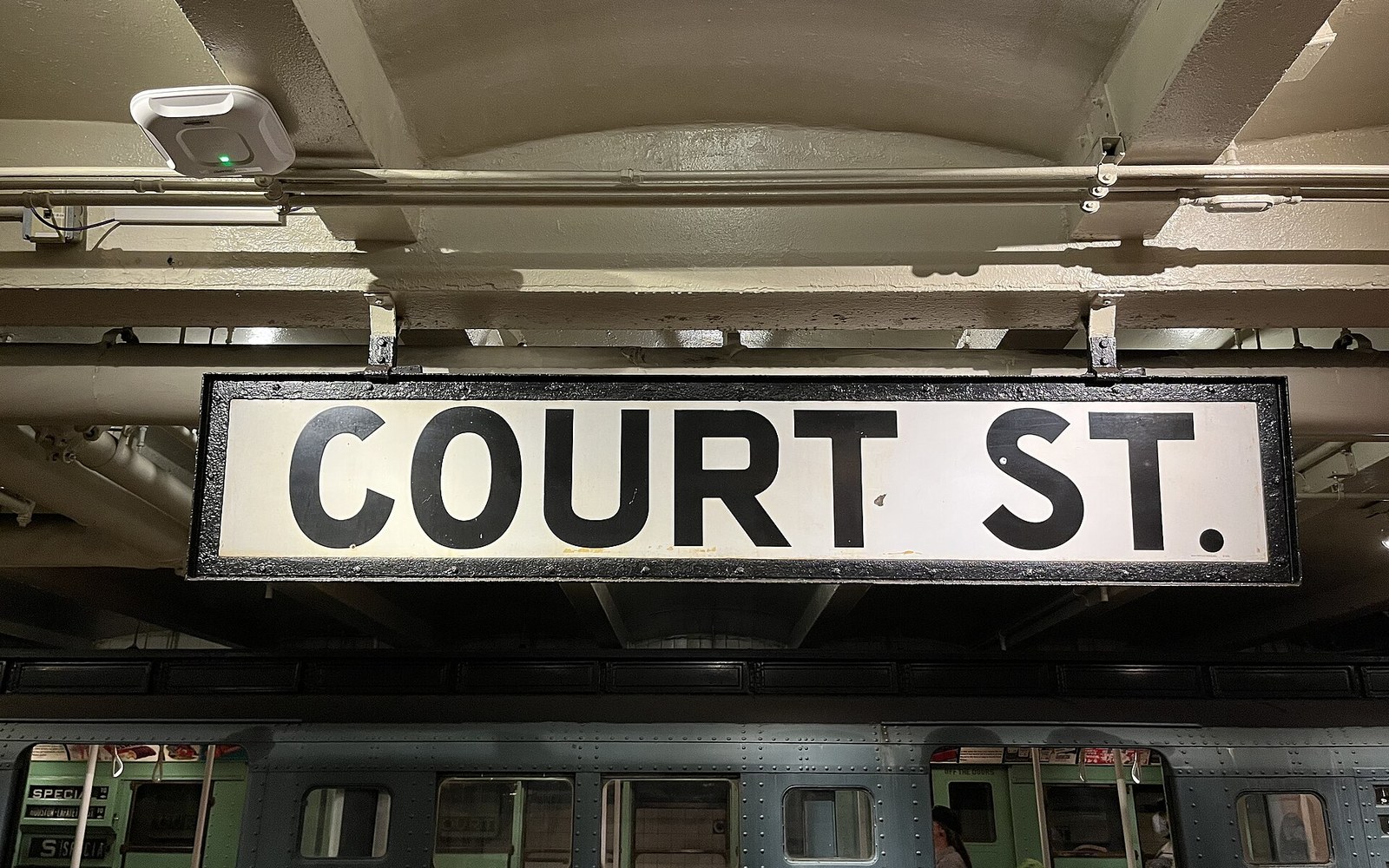 Court St. subway station sign hangs above vintage subway cars on the platform