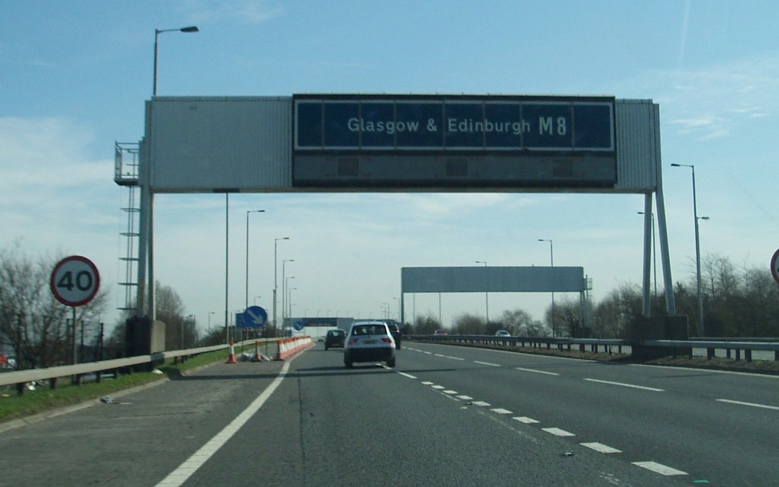 Overhead gantry sign directing traffic to Glasgow and Edinburgh via the M8 motorway