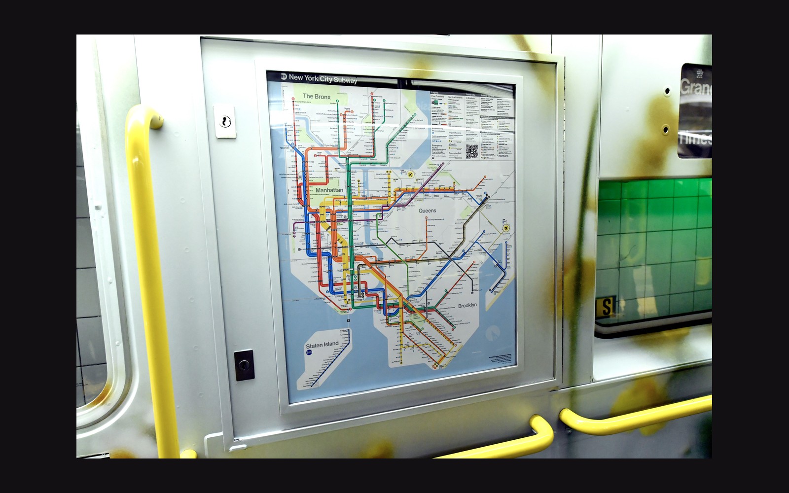 New York City subway map posted inside a train car with yellow handrails